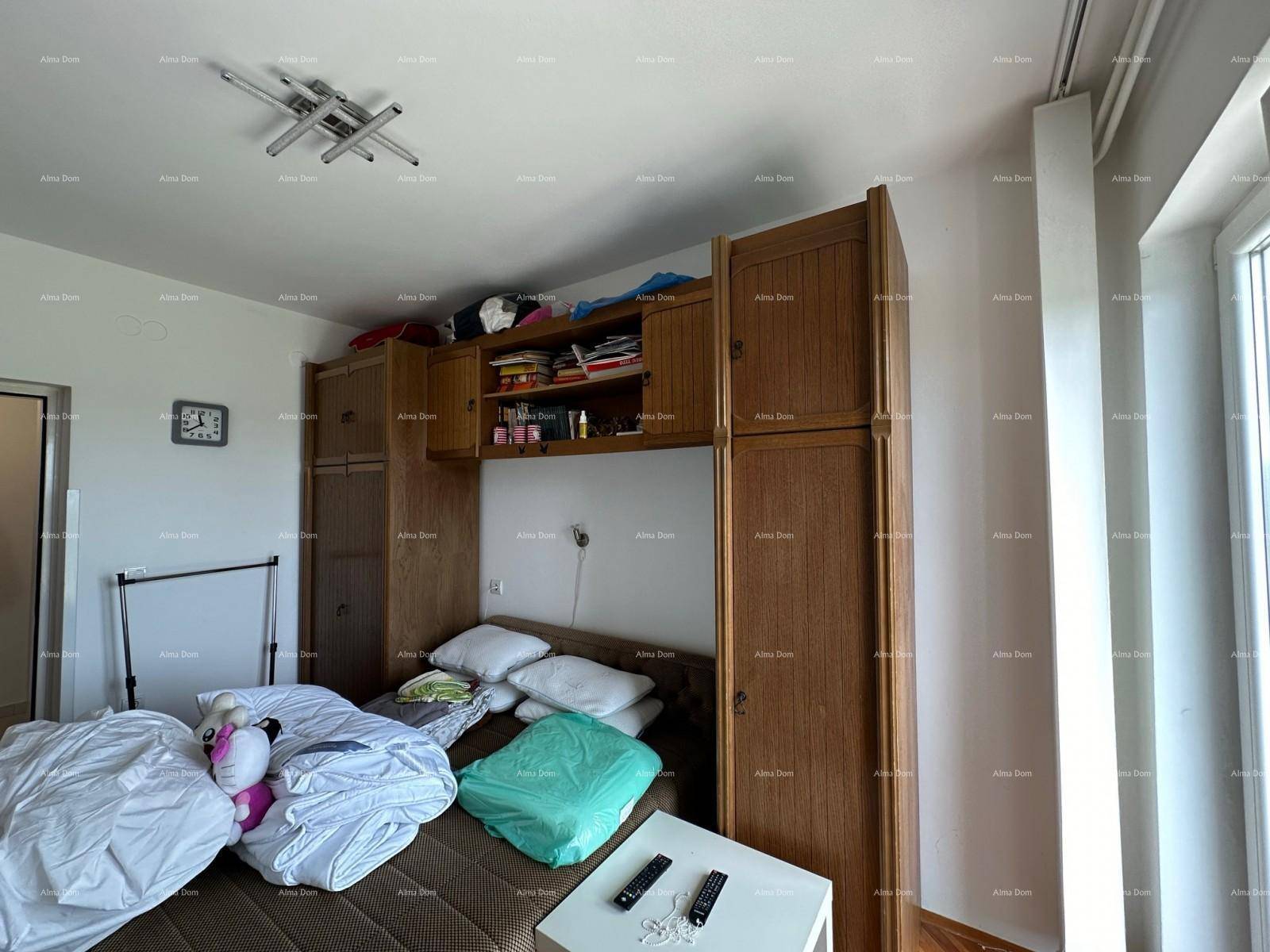 Helles Schlafzimmer mit Holzeinbaumöbeln und Blick nach draußen durch das Fenster.