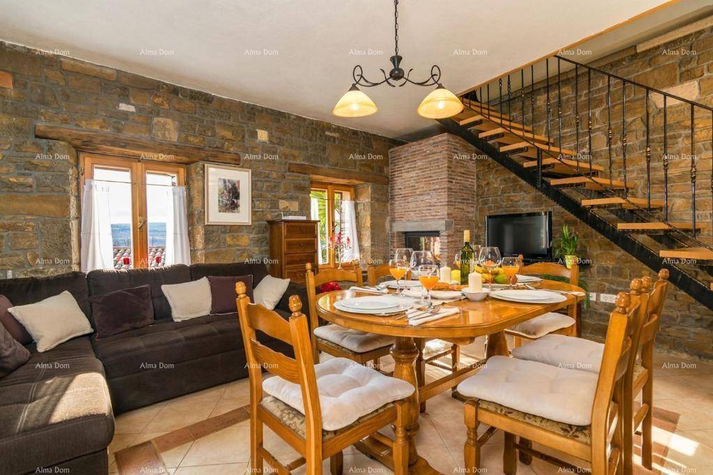 Rustikaler Wohn-Essbereich mit Steinfliesen, Kamin, Sofa und offener Treppe.