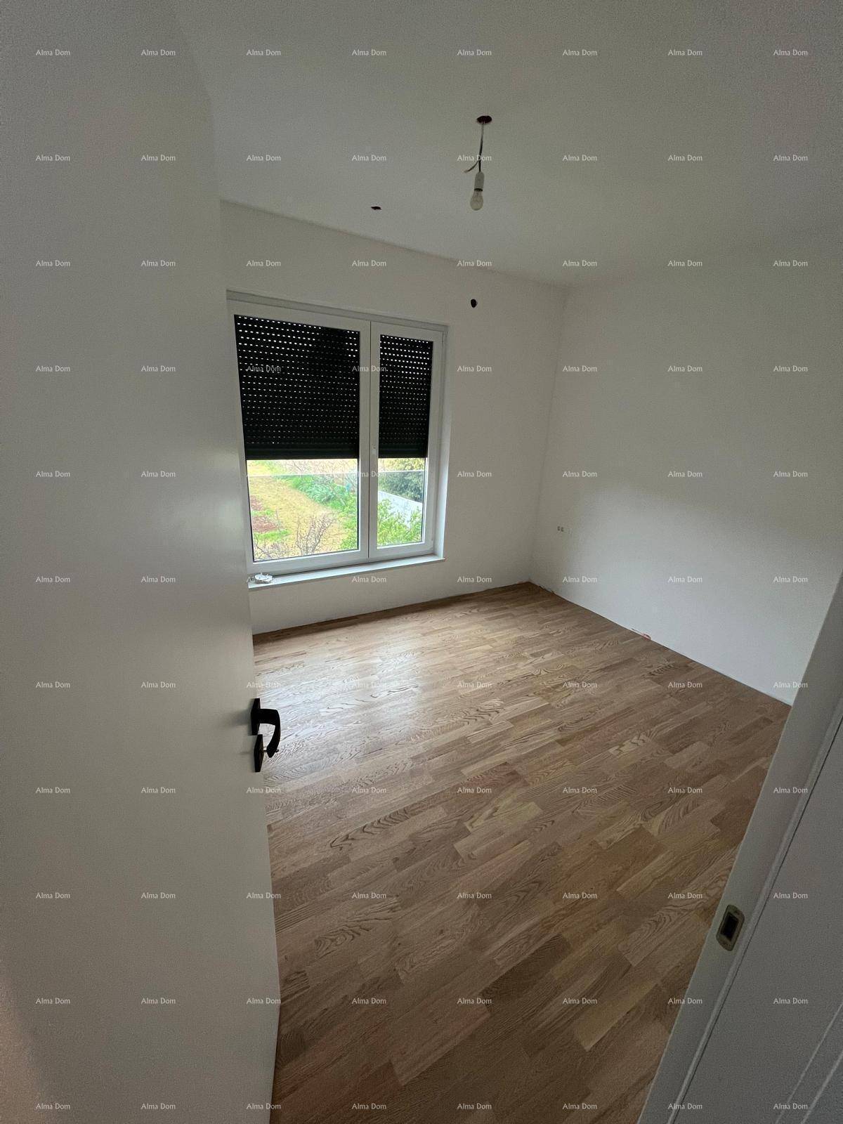 Leeres Zimmer mit hellem Parkettboden, weißen Wänden und einem Fenster mit geschlossenen Rollläden.