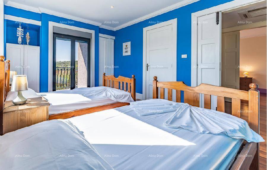 Kinderzimmer mit zwei Betten, blauen Wänden und Zugang zu einem französischen Balkon.