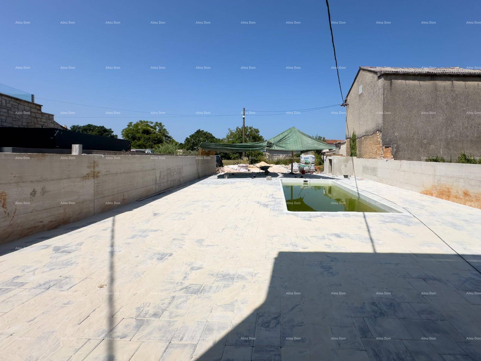Weitläufiger Außenbereich mit Pool in Bau und großer gepflasterter Fläche unter klarem Himmel.