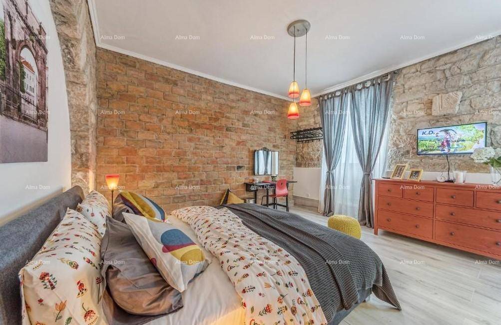 Schlafzimmer mit freigelegter Ziegelwand, Holzboden und einem großen Bett mit bunten Kissen.