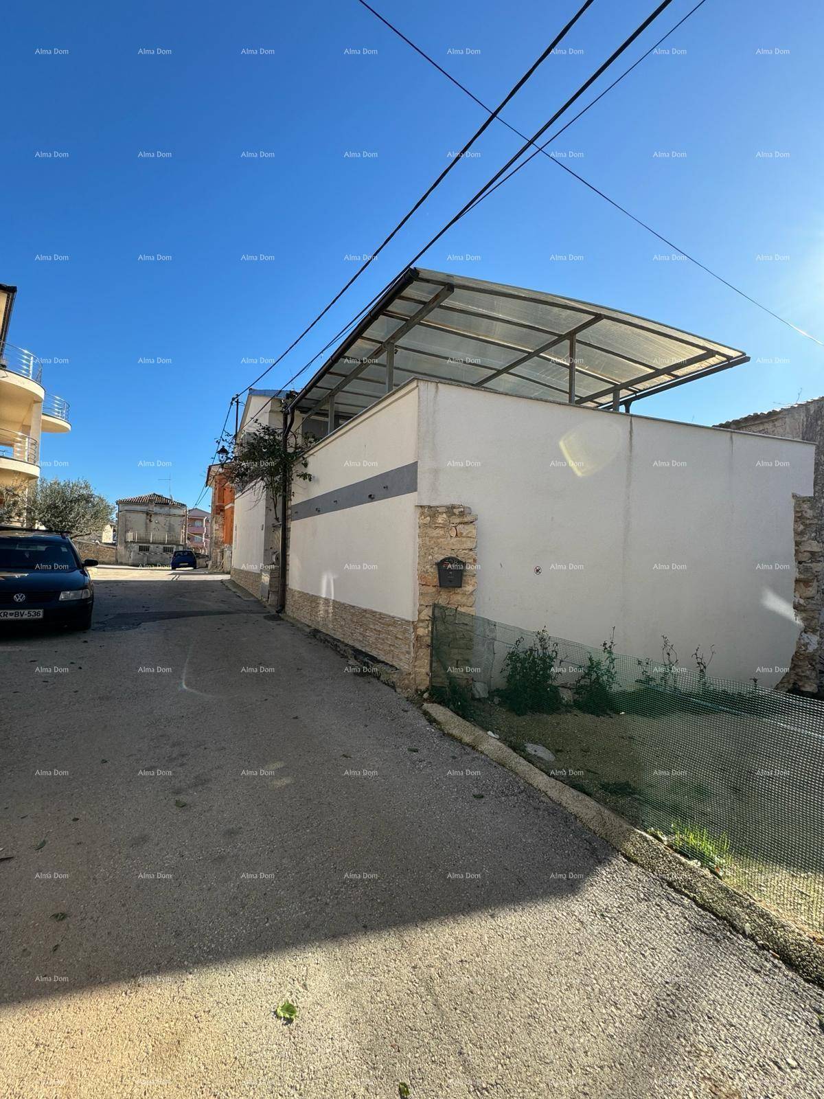 Seitenansicht des Gebäudes mit einer überdachten Terrasse und Steinverkleidung an der Fassade.