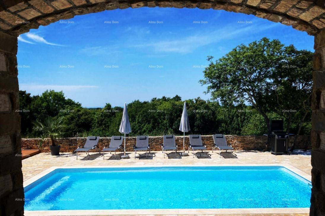 Blick durch einen Steinbogen auf den Poolbereich mit Liegestühlen und üppiger grüner Landschaft.