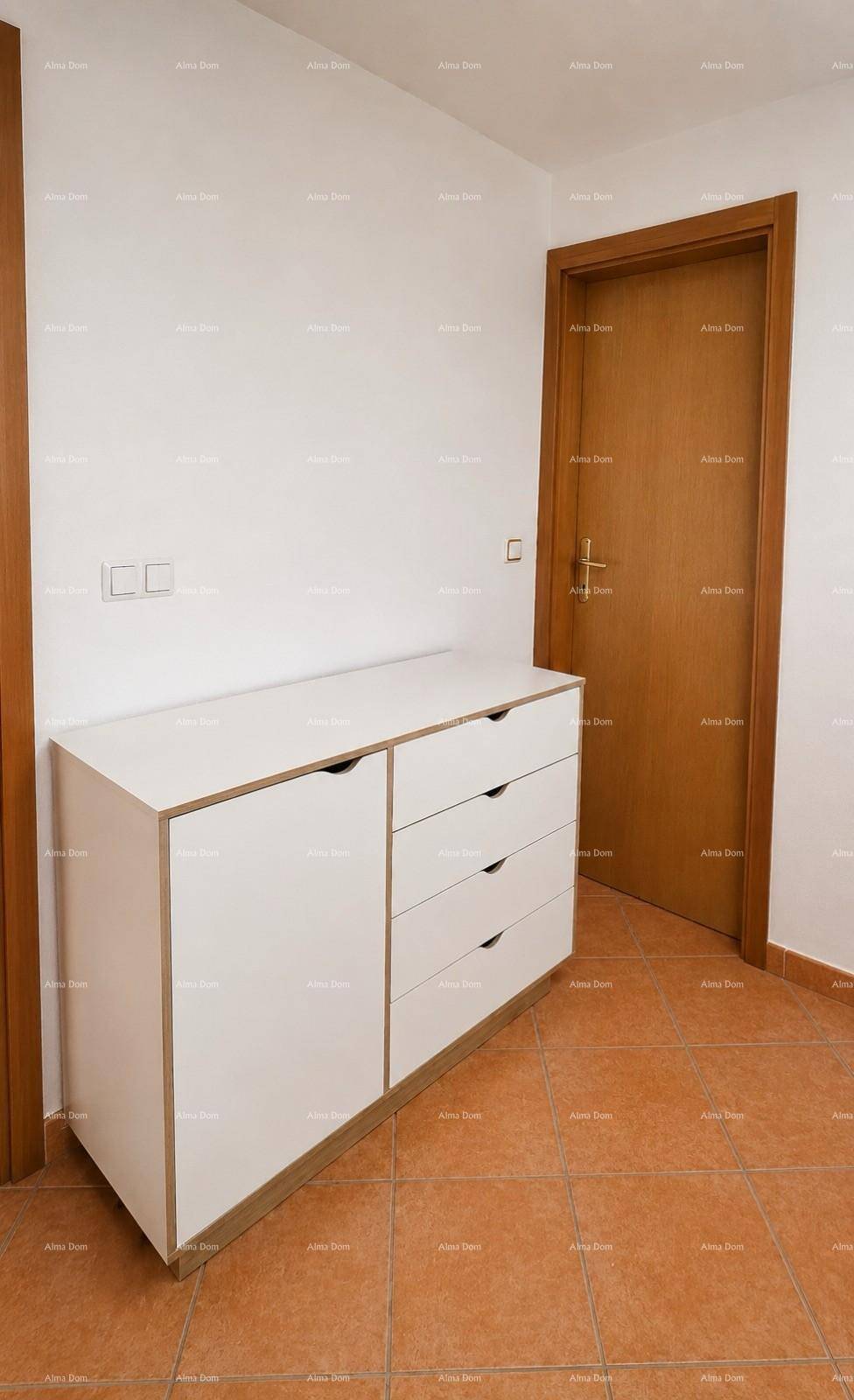 Heller Flurbereich mit weißer Kommode und Holztüren, bietet zusätzlichen Stauraum.