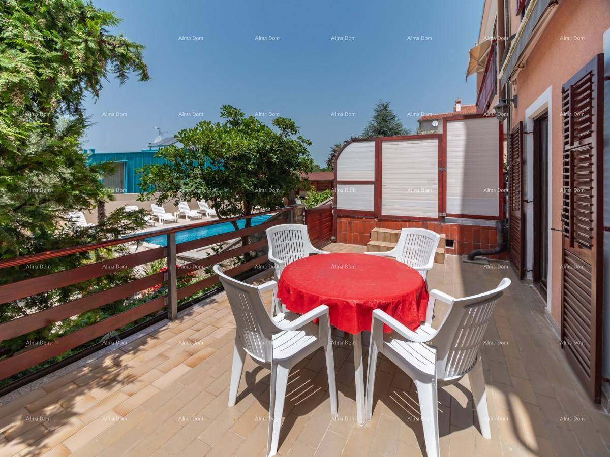 Sonniger Terrassenbereich mit Esstisch und Stühlen, ideal für Mahlzeiten im Freien mit Poolblick.