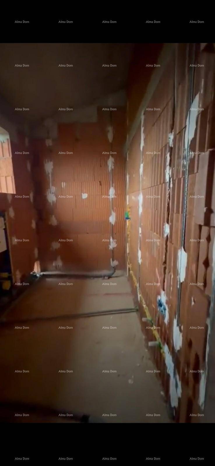 Innenraum im Rohbau mit sichtbaren Wasserleitungen und unverputzten Ziegelwänden.