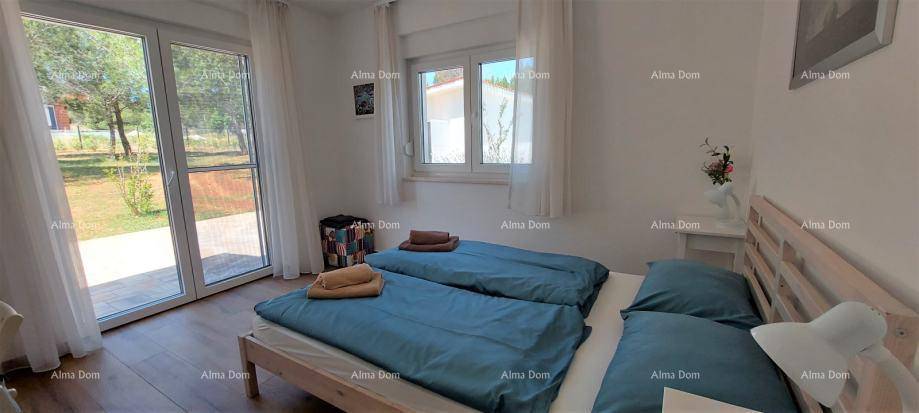 Helles Schlafzimmer mit Doppelbett und großen Fenstertüren, die Zugang zum Garten oder zur Terrasse bieten.