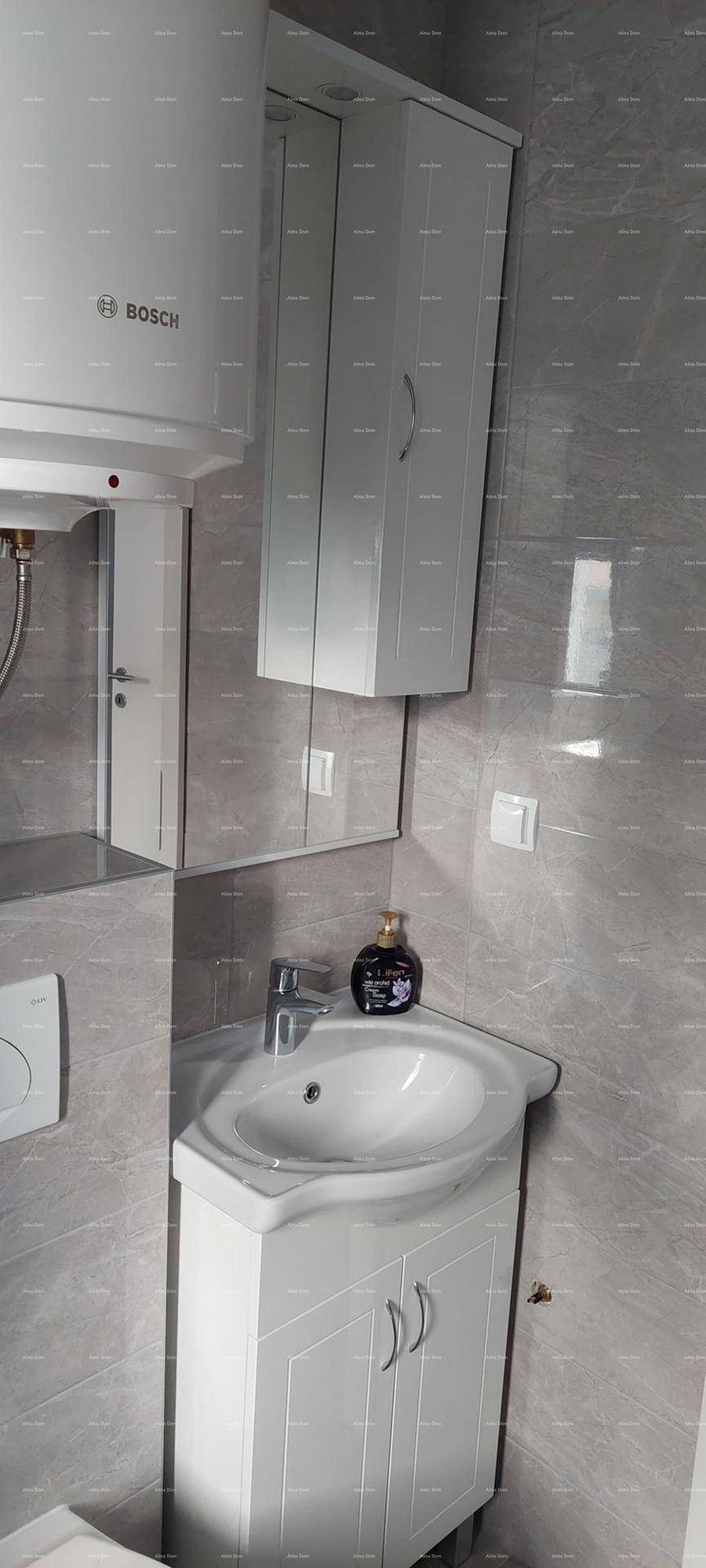 Badezimmer mit Waschbecken, Spiegelschrank und Warmwasserboiler über dem Spiegel.