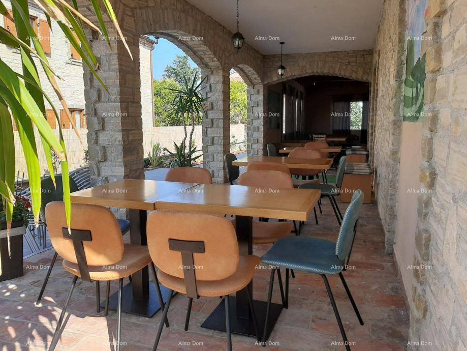 Überdachte Terrasse mit Steinbögen, mehreren Tischen und Blick ins Grüne.