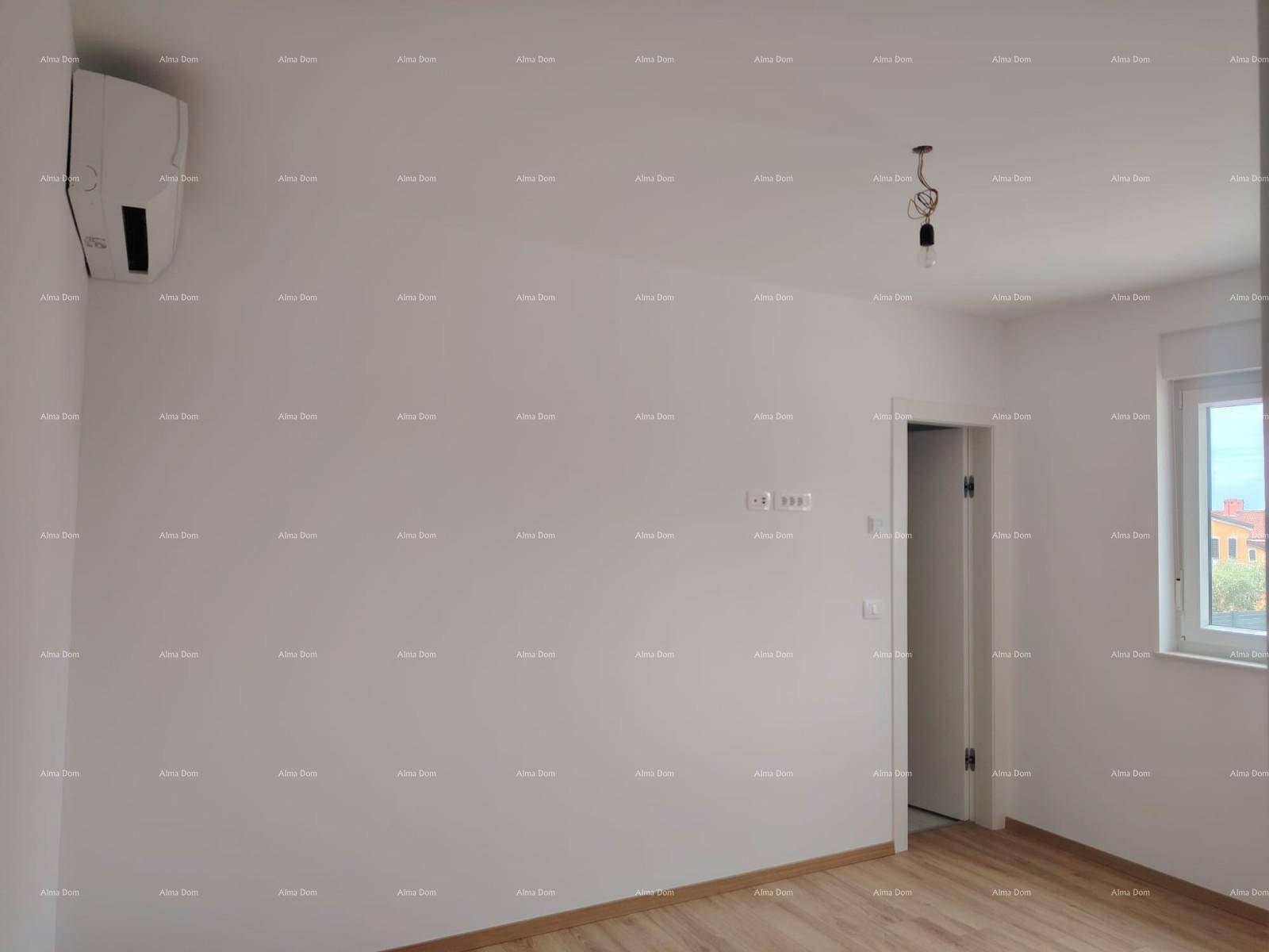 Leeres Schlafzimmer mit hellem Laminatboden und Klimaanlage, bereit zur individuellen Gestaltung.