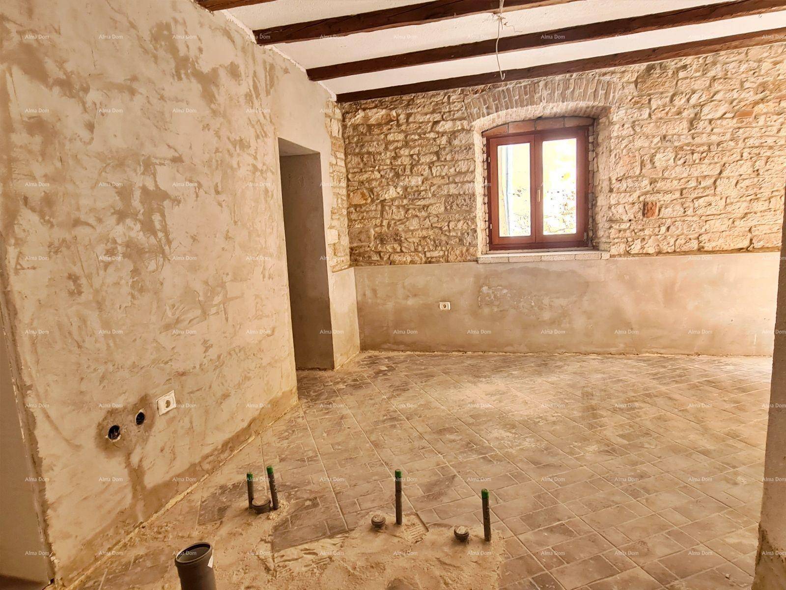 Rohbau eines Wohnzimmers mit freigelegten Holzbalken, Steinwand und Installationsvorbereitungen.