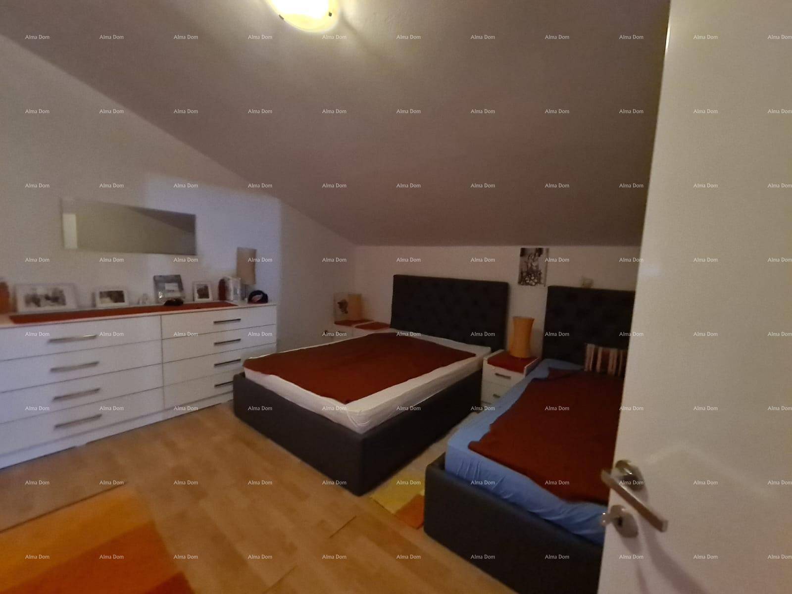 Helles Schlafzimmer im Dachgeschoss mit zwei Betten, Kommode und Holzboden.