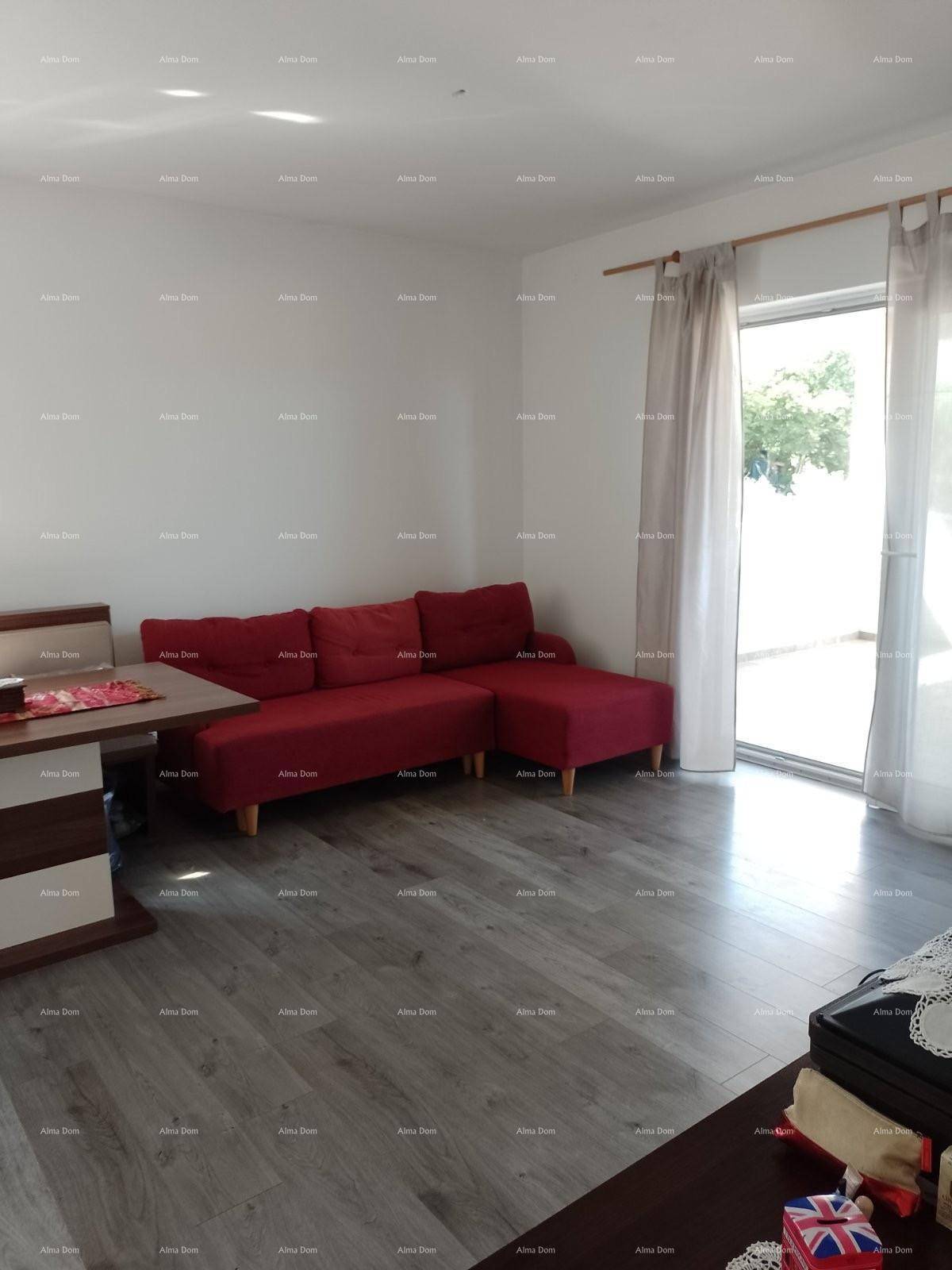Heller Wohnbereich mit rotem Sofa, Holztisch und Laminatboden, gut beleuchtet.