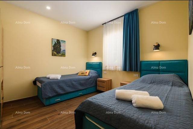 Kinder- oder Gästezimmer mit zwei Einzelbetten, Holzböden und blauen Vorhängen.