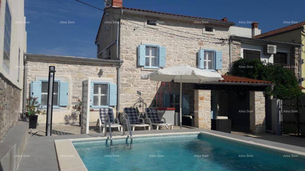 Charmantes Steinhaus mit Pool, umgeben von einer Terrasse mit Sonnenliegen und einem Sonnenschirm für heiße Tage.