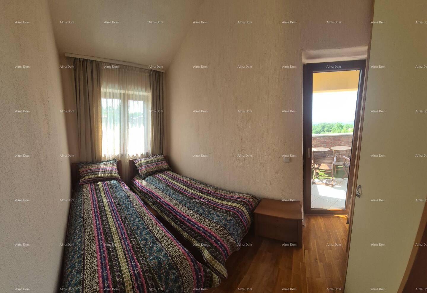 Schlafzimmer mit zwei Einzelbetten, Holzboden und Zugang zu einem Balkon mit Ausblick.