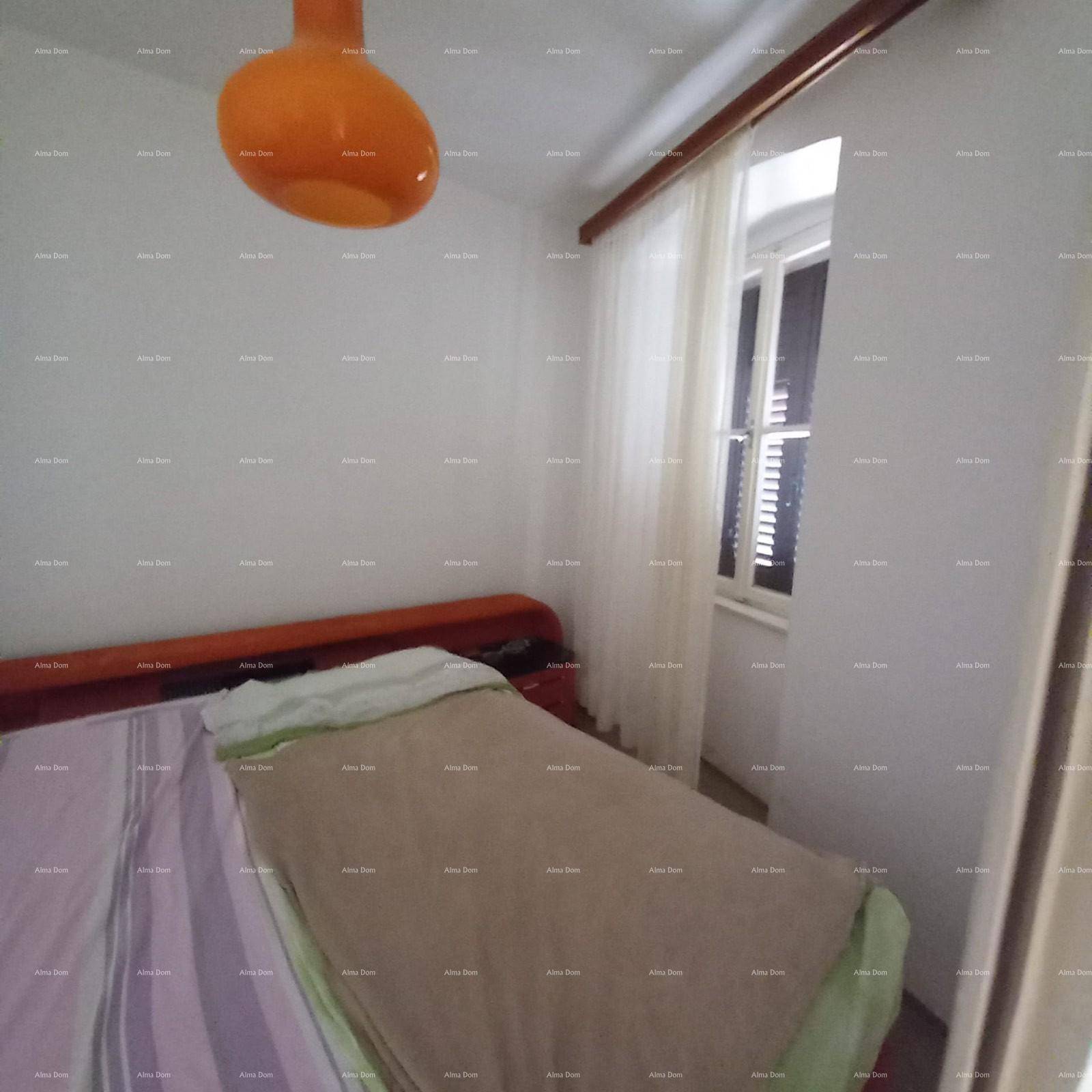 Einfaches Schlafzimmer mit Bett, Fenster und einem orangefarbenen Deckenlicht.