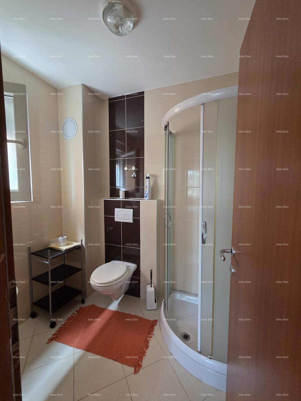 Modernes Badezimmer mit Duschkabine, Wand-WC und beigen sowie braunen Fliesen.