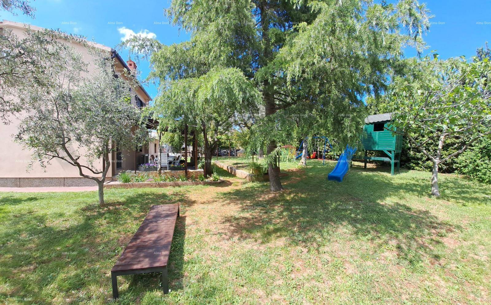 Großer Garten mit Bäumen, Rasenfläche und einem Spielhaus mit Rutsche für Kinder.