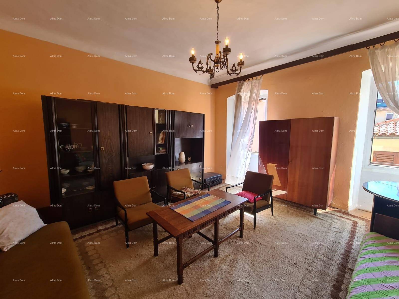 Geräumiges Wohnzimmer mit orangefarbenen Wänden, Teppichboden und dunklen Holzmöbeln.