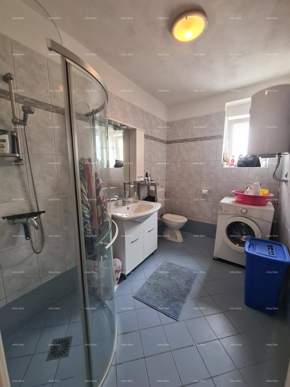 Badezimmer mit Duschkabine, Waschbecken, Toilette und Waschmaschine, hell gefliest und funktional.