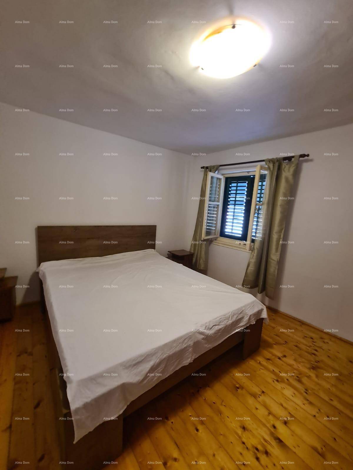 Schlafzimmer mit Doppelbett, Holzboden und Fenster mit Fensterläden.