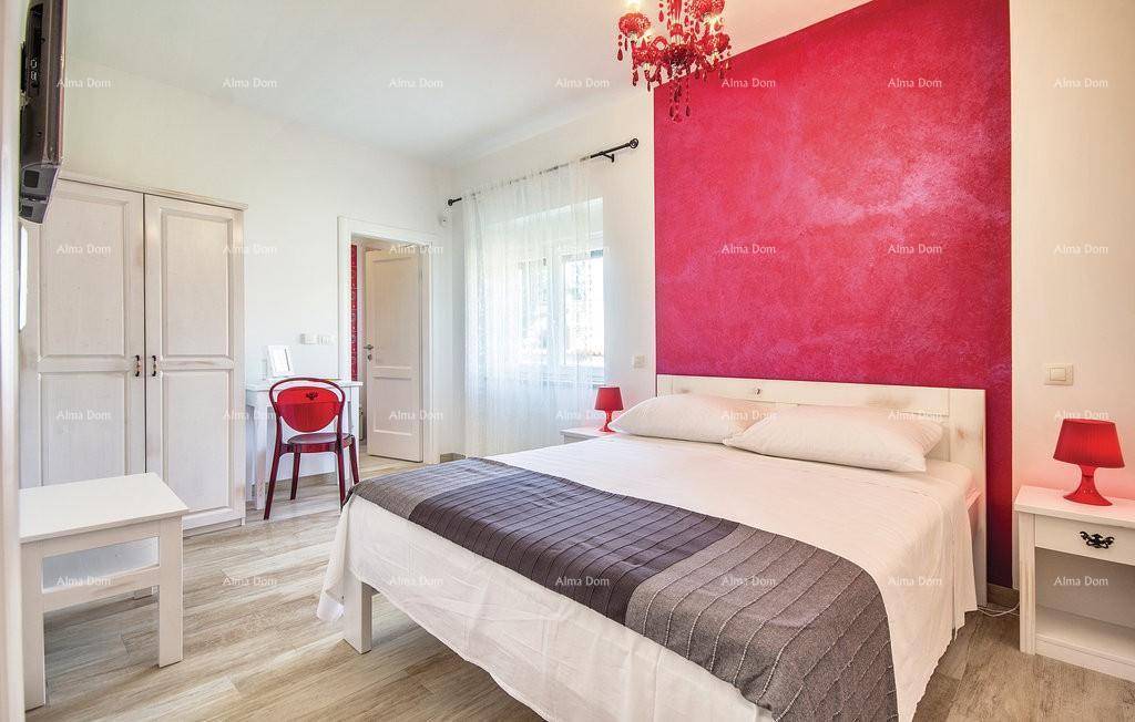 Helles Schlafzimmer mit roter Akzentwand, Doppelbett und modernem Kronleuchter.
