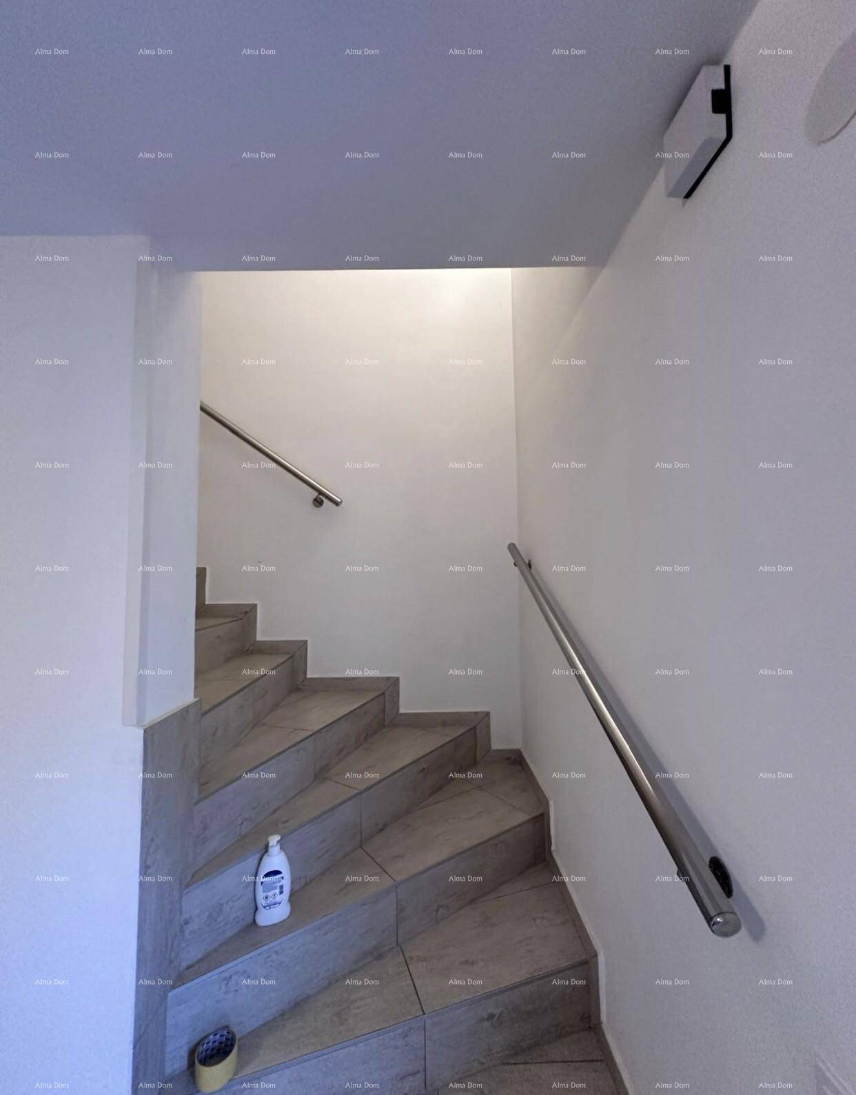 Moderner Treppenaufgang mit Fliesenstufen und zwei Edelstahlhandläufen an den Wänden.