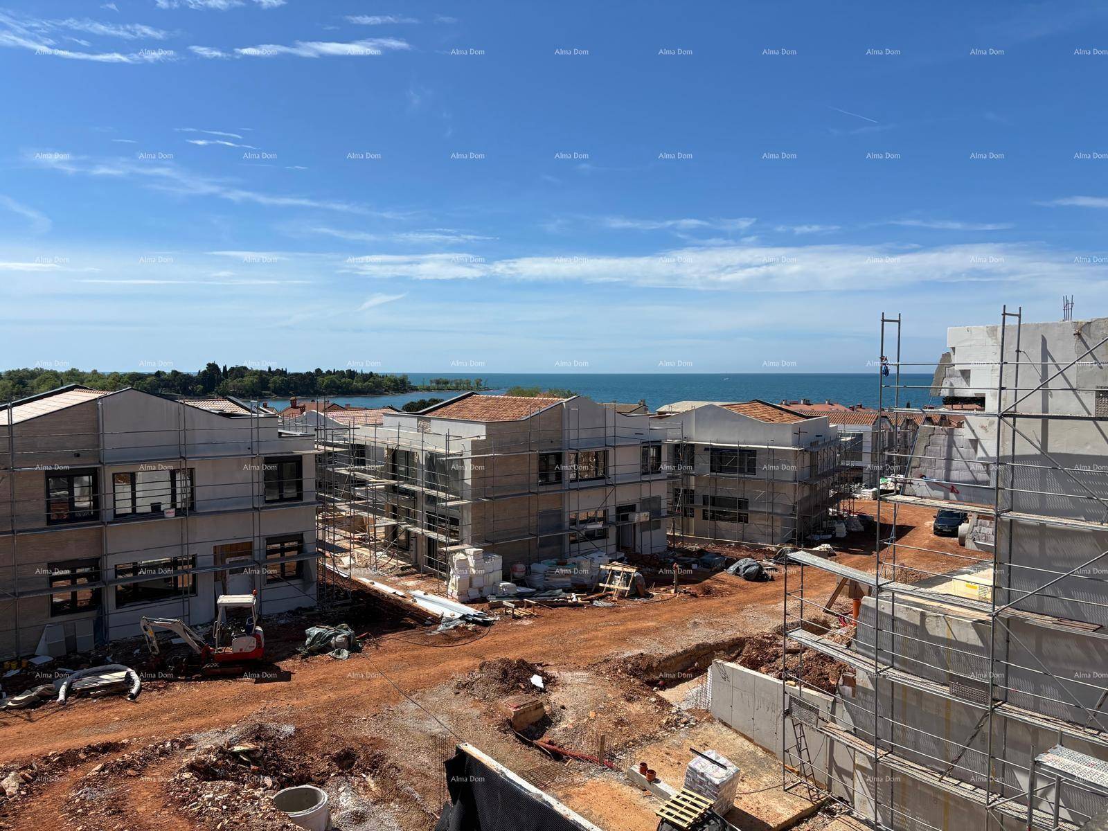 Baustelle eines Wohnkomplexes mit mehreren Gebäuden im Bau und weitem Meerblick im Hintergrund.