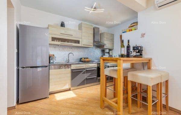 Moderne Küche mit hellen Holzschränken, Kühlschrank und einer kleinen Frühstückstheke mit Hockern.