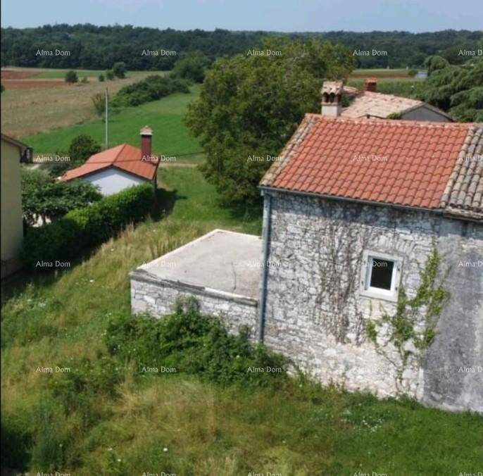 Altes Steinhaus mit Ziegeldach und weitem Blick über die ländliche Landschaft und grüne Felder.
