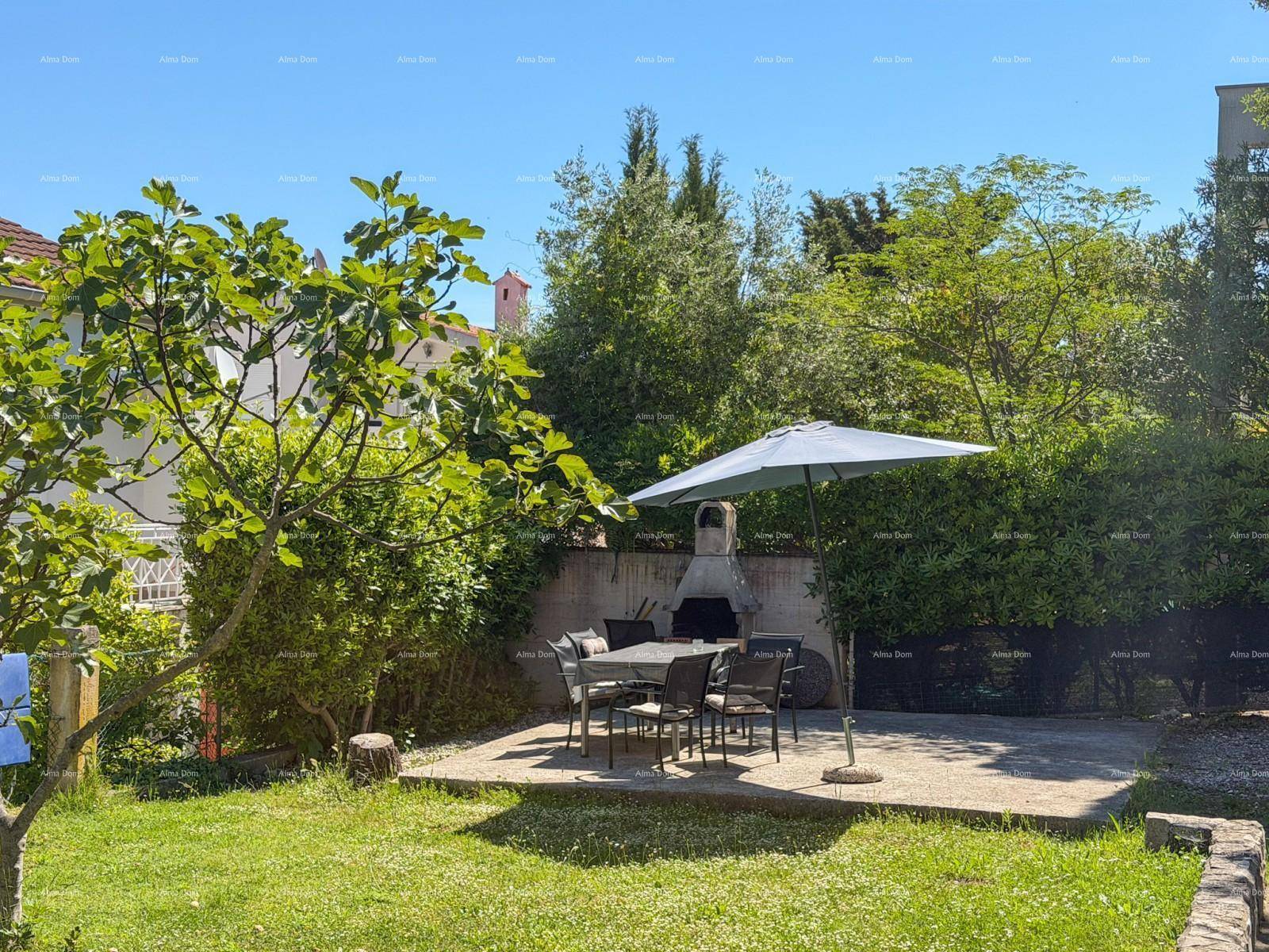 Gartenbereich mit Essplatz im Freien, Sonnenschirm und einem gemauerten Grill.