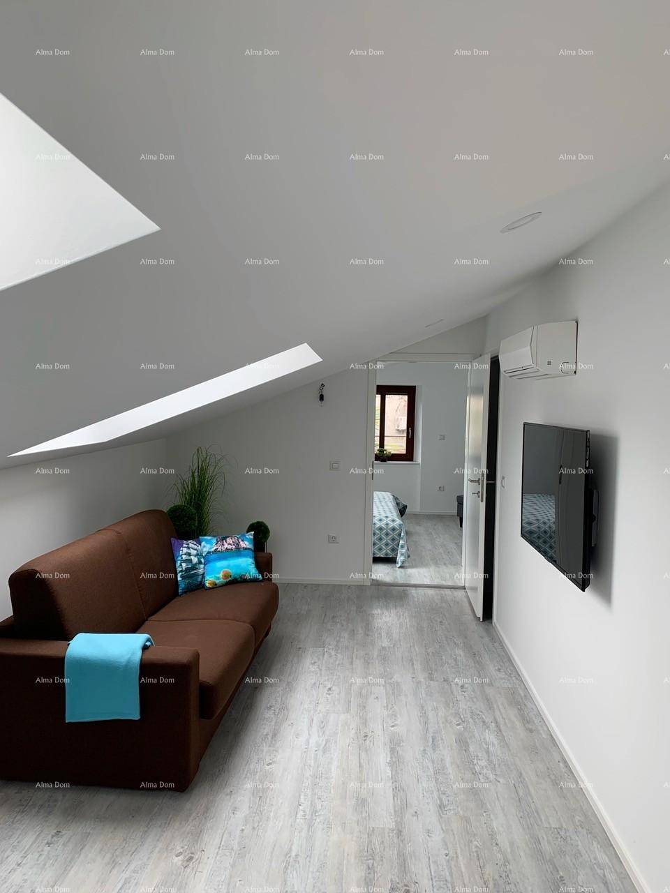 Wohnbereich mit bequemer Couch, Wandfernseher und Zugang zu einem angrenzenden Schlafzimmer.
