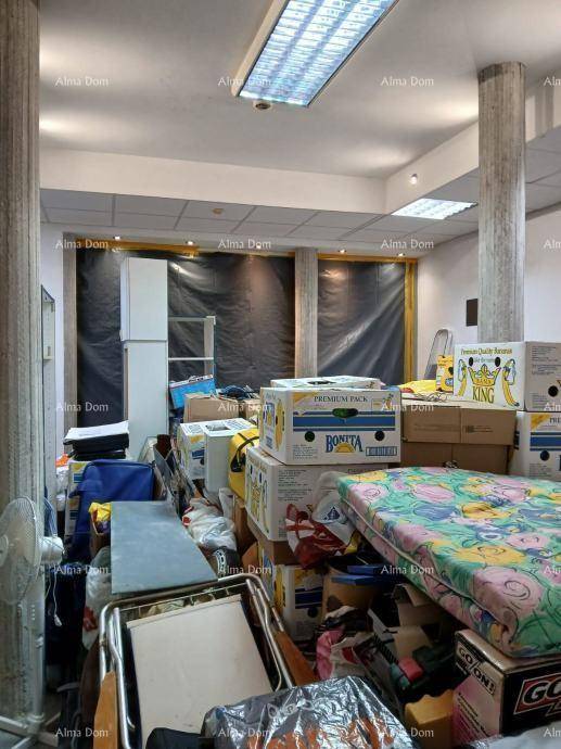 Überfüllter Raum mit Kartons, Matratze und einem Ventilator, Fenster sind abgedeckt.