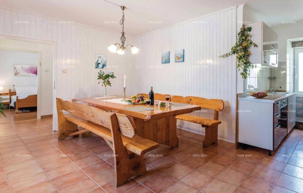 Offener Wohn- und Essbereich mit rustikalem Holztisch und Zugang zu einem Schlafzimmer.