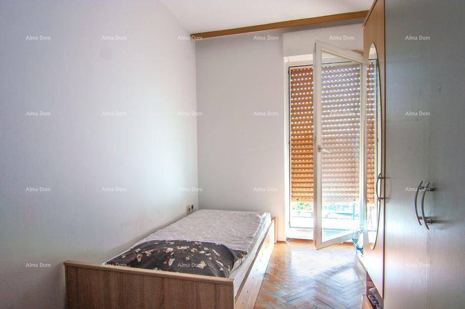 Kleines Schlafzimmer mit Einzelbett, Holzboden und einem Fenster mit Rollläden.