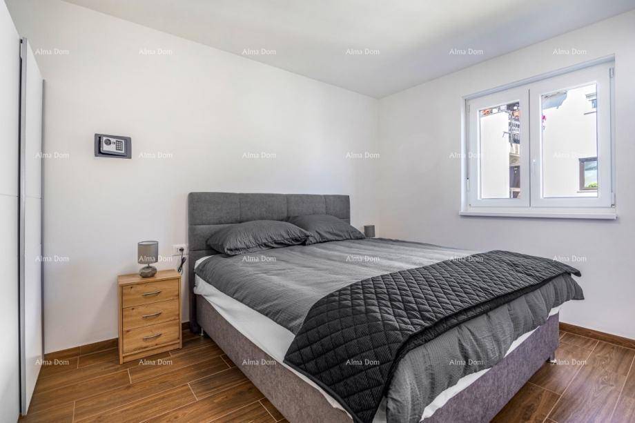 Helles Schlafzimmer mit Doppelbett, Holzfußboden und einem Fenster mit Blick nach draußen.