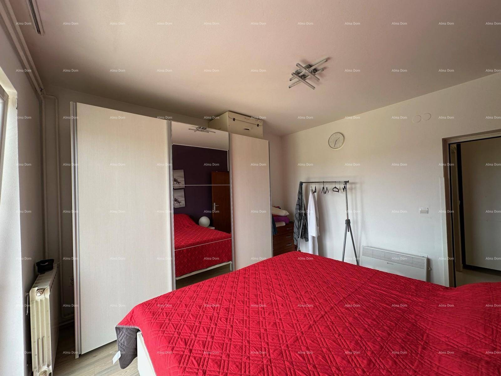 Schlafzimmer mit rotem Bett, großem weißen Kleiderschrank und praktischem Kleiderständer.