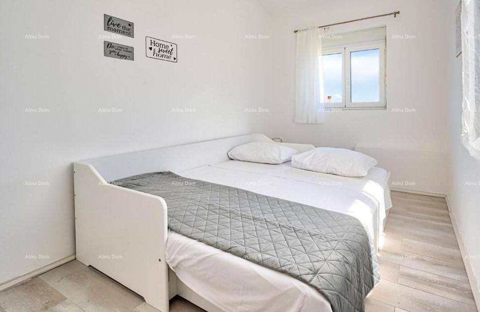 Kleines Schlafzimmer mit Einzelbett, Holzboden und Fenster mit Tageslicht.