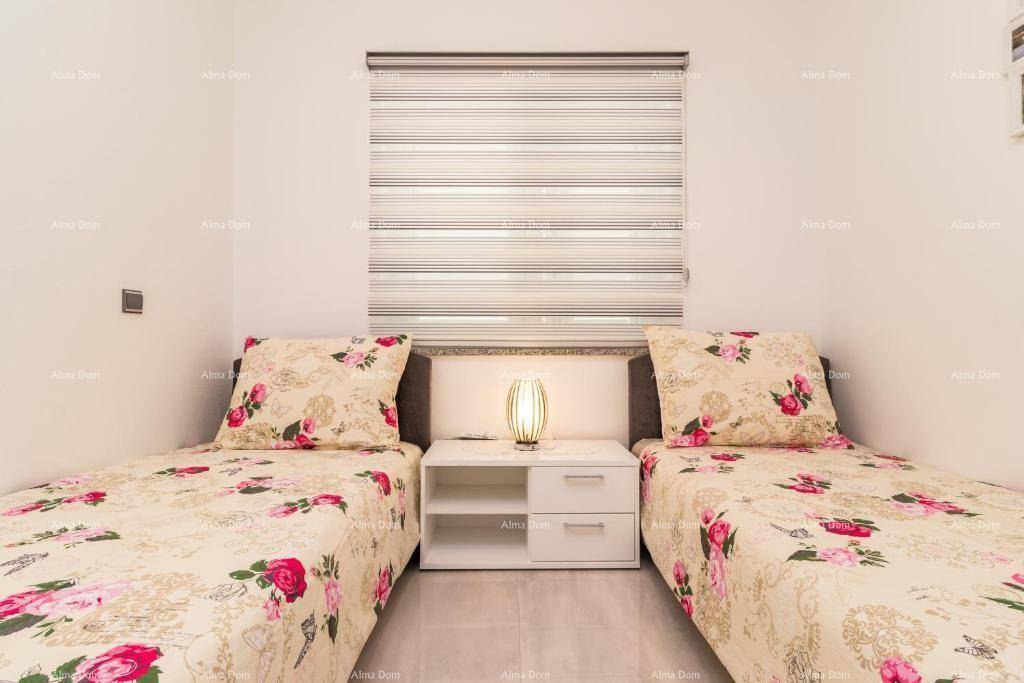 Helles Schlafzimmer mit zwei Einzelbetten, floraler Bettwäsche und einem Nachttisch mit Lampe.