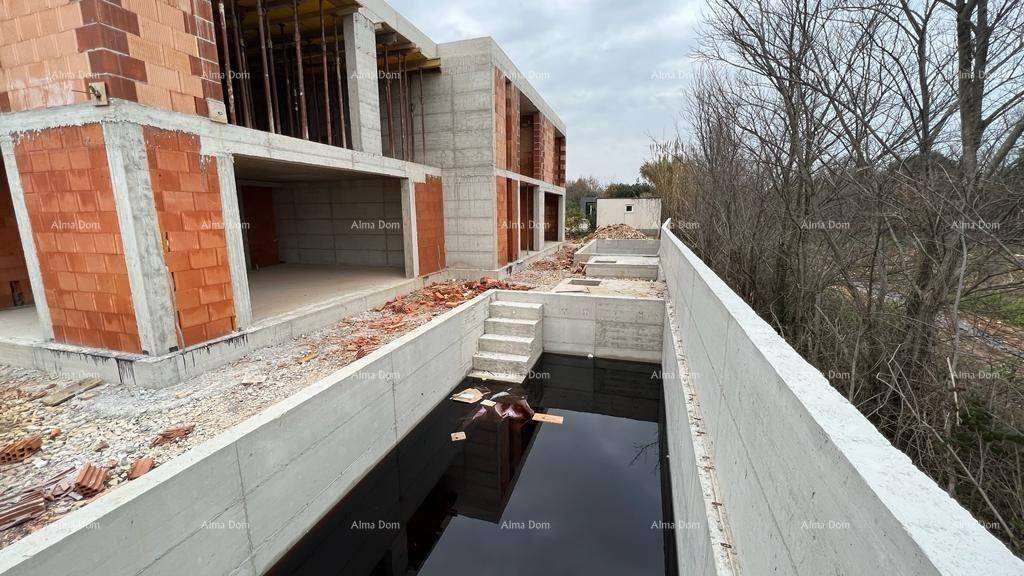 Unfertige Poolstruktur neben dem Rohbau des Hauses, gefüllt mit Wasser.