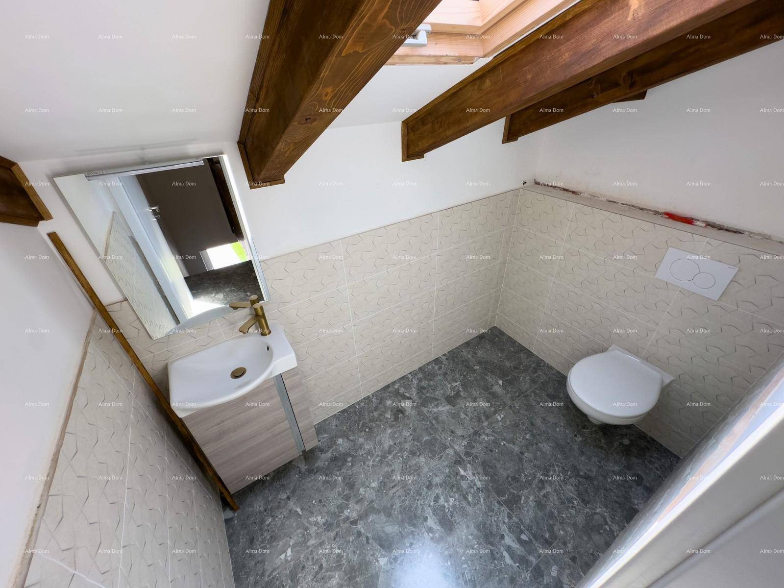 Badezimmer von oben gesehen, mit Waschtisch, Wand-WC, Holzbalken und Dachfenster, hell gefliest.