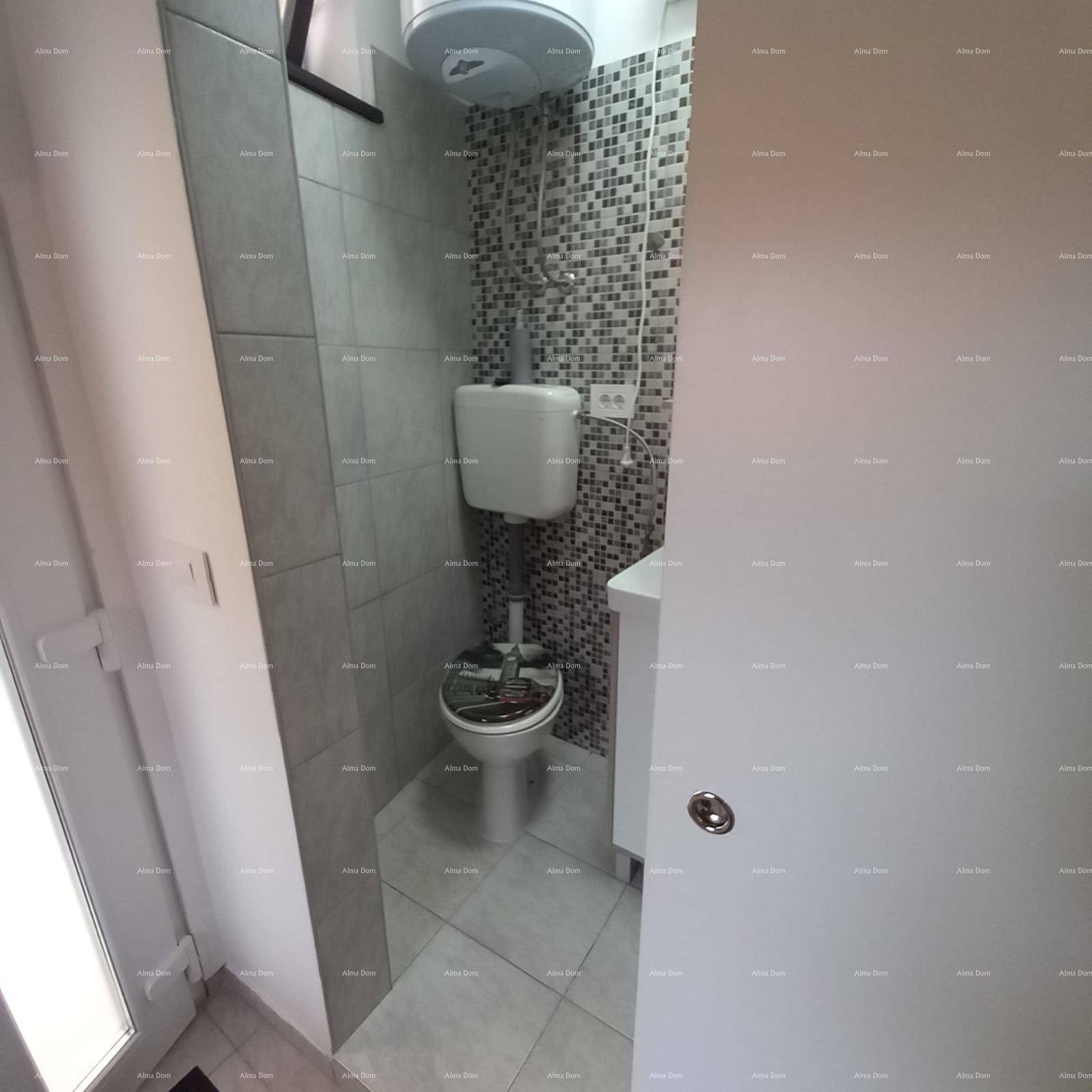 Kleines WC mit Wandfliesen in Grautönen und einem kompakten Waschbecken.