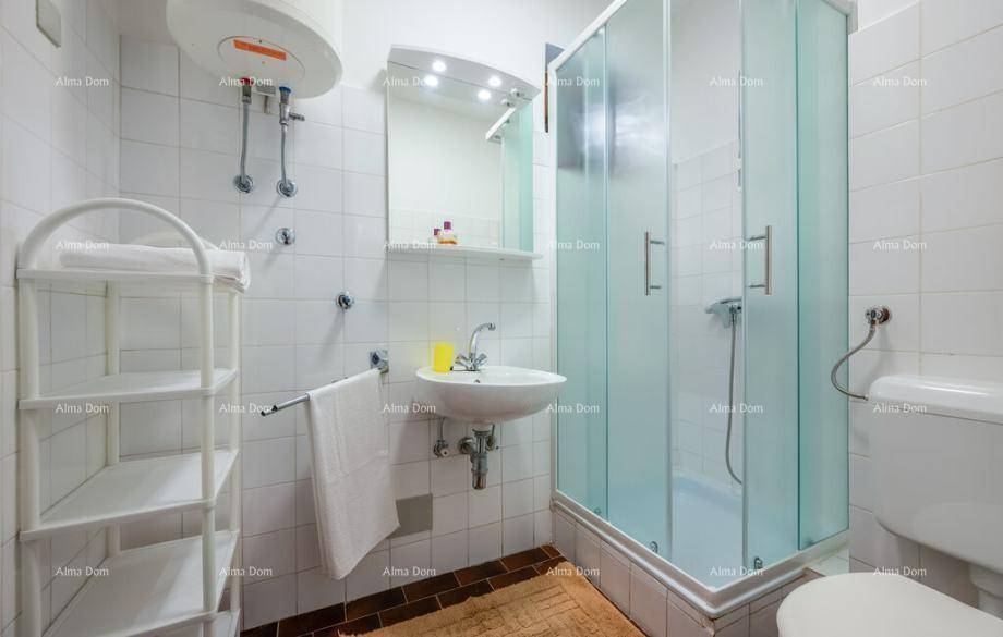 Funktionales Badezimmer mit Duschkabine, Waschbecken und WC, komplett gefliest und hell.