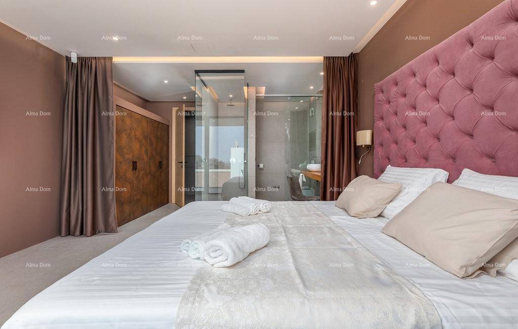 Elegantes Schlafzimmer mit großem, gepolstertem Kopfteil und offenem Zugang zum modernen Badezimmer.