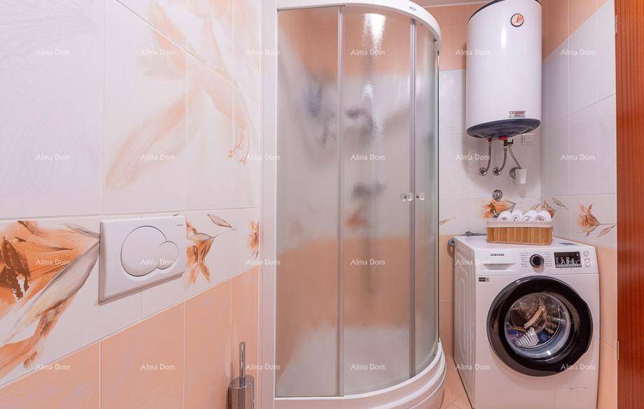 Badezimmer mit Duschkabine, Waschmaschine und floralen Fliesen in Pastelltönen.