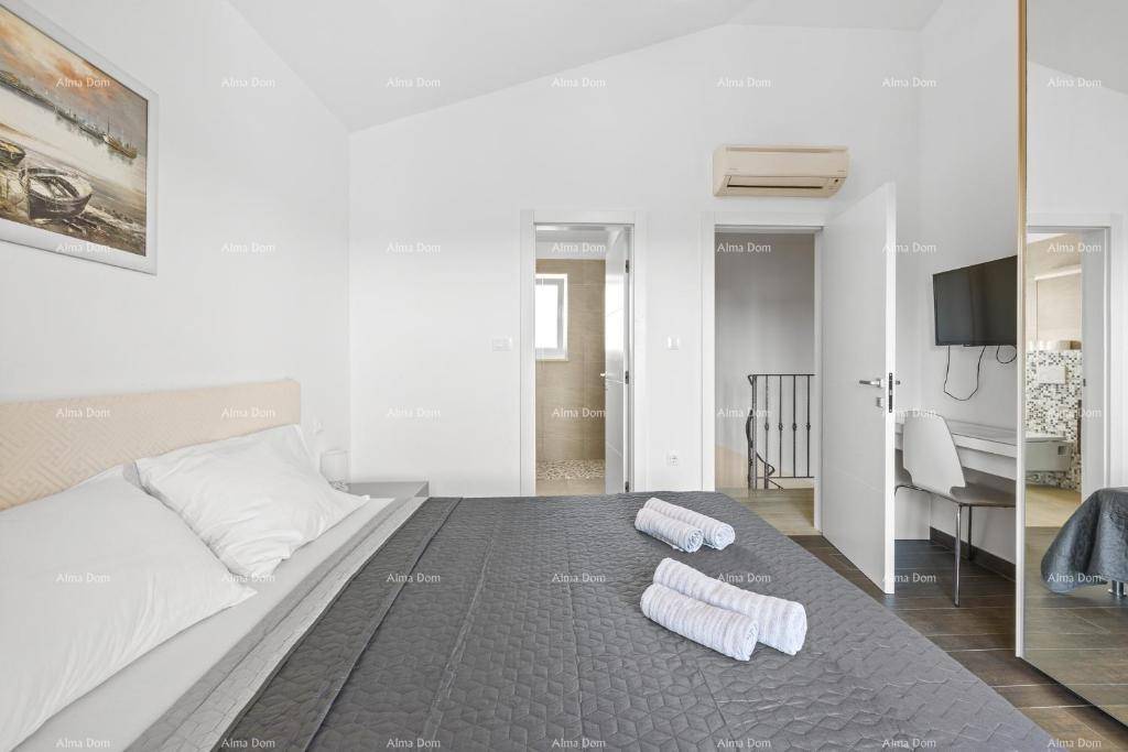 Schlafzimmer mit Doppelbett, dunklem Boden und Zugang zu einem modernen Badezimmer.
