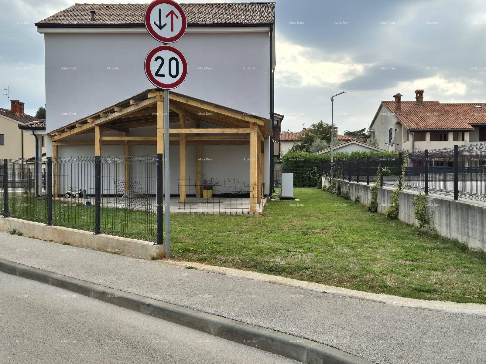 Seitenansicht des Hauses mit einem Holz-Carport und einer Rasenfläche neben der Straße.