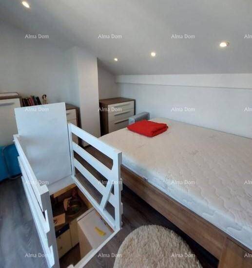 Helles Schlafzimmer mit Einzelbett und Zugang zu einer unteren Ebene, unter einer schrägen Decke.